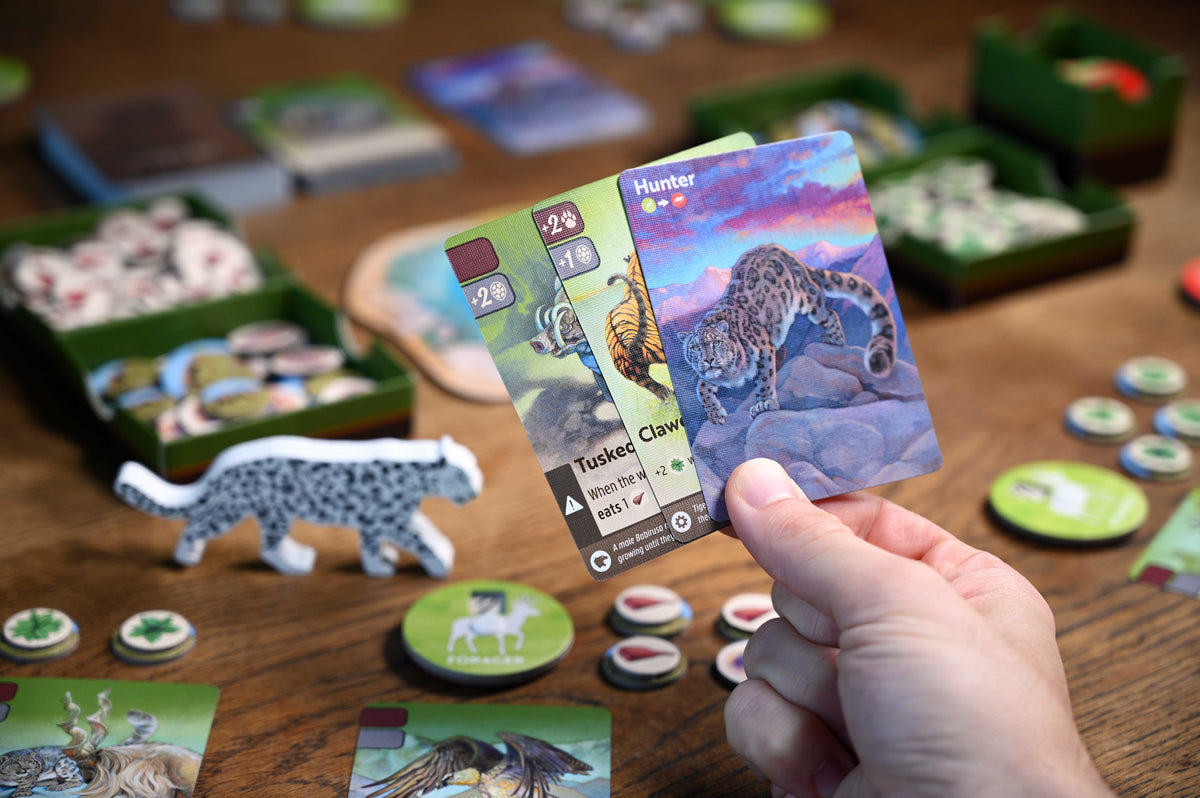 Hand holding a card with a leopard illustration in a board game setting