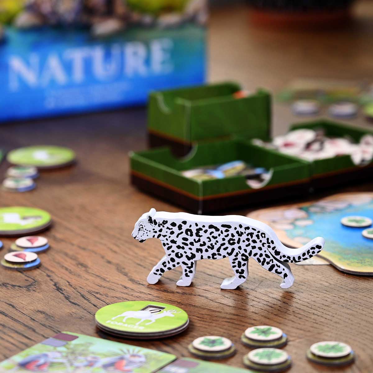 Board game with a leopard figurine and nature-themed cards on a wooden table